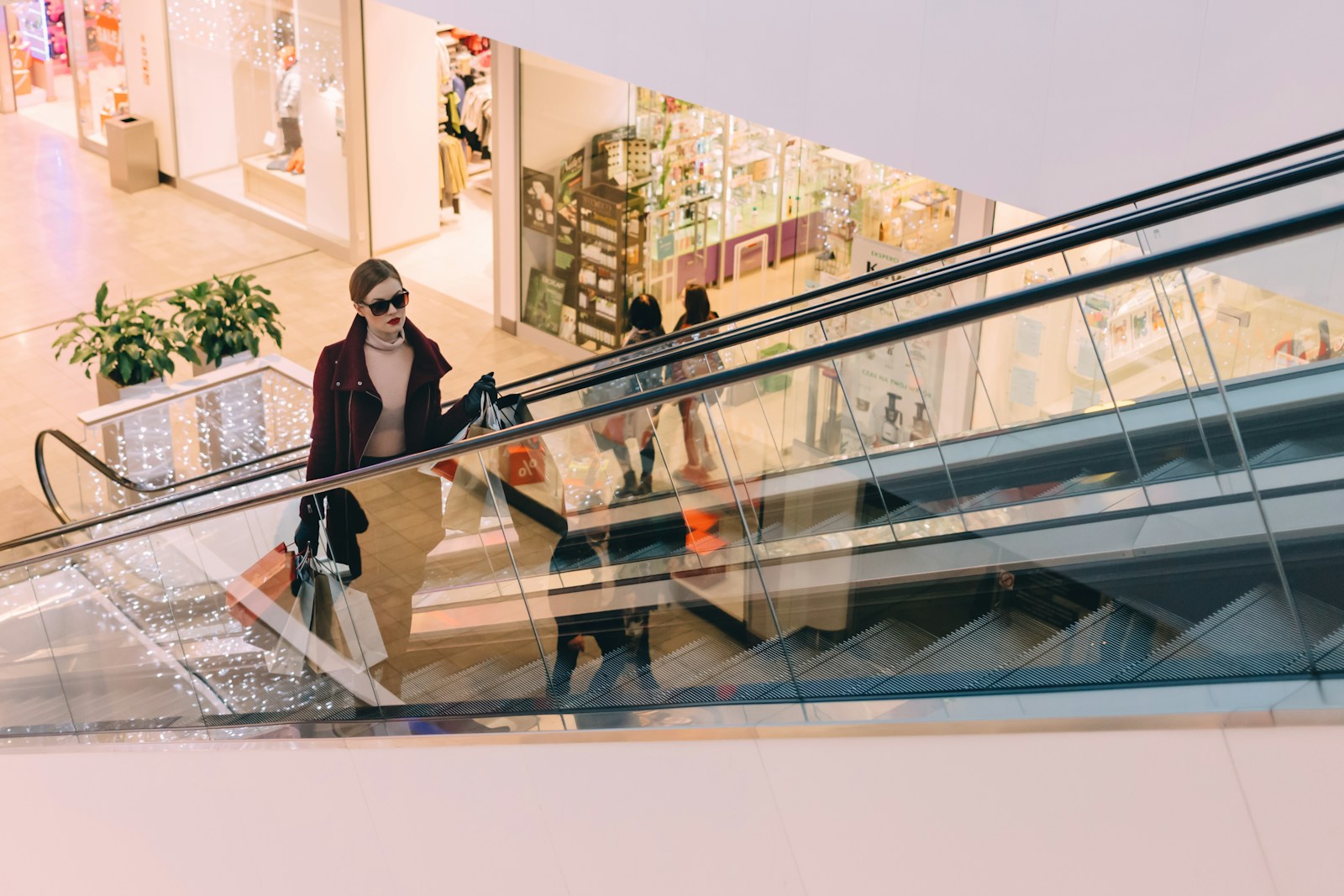 woman riding escalator inside one of the shopping centers